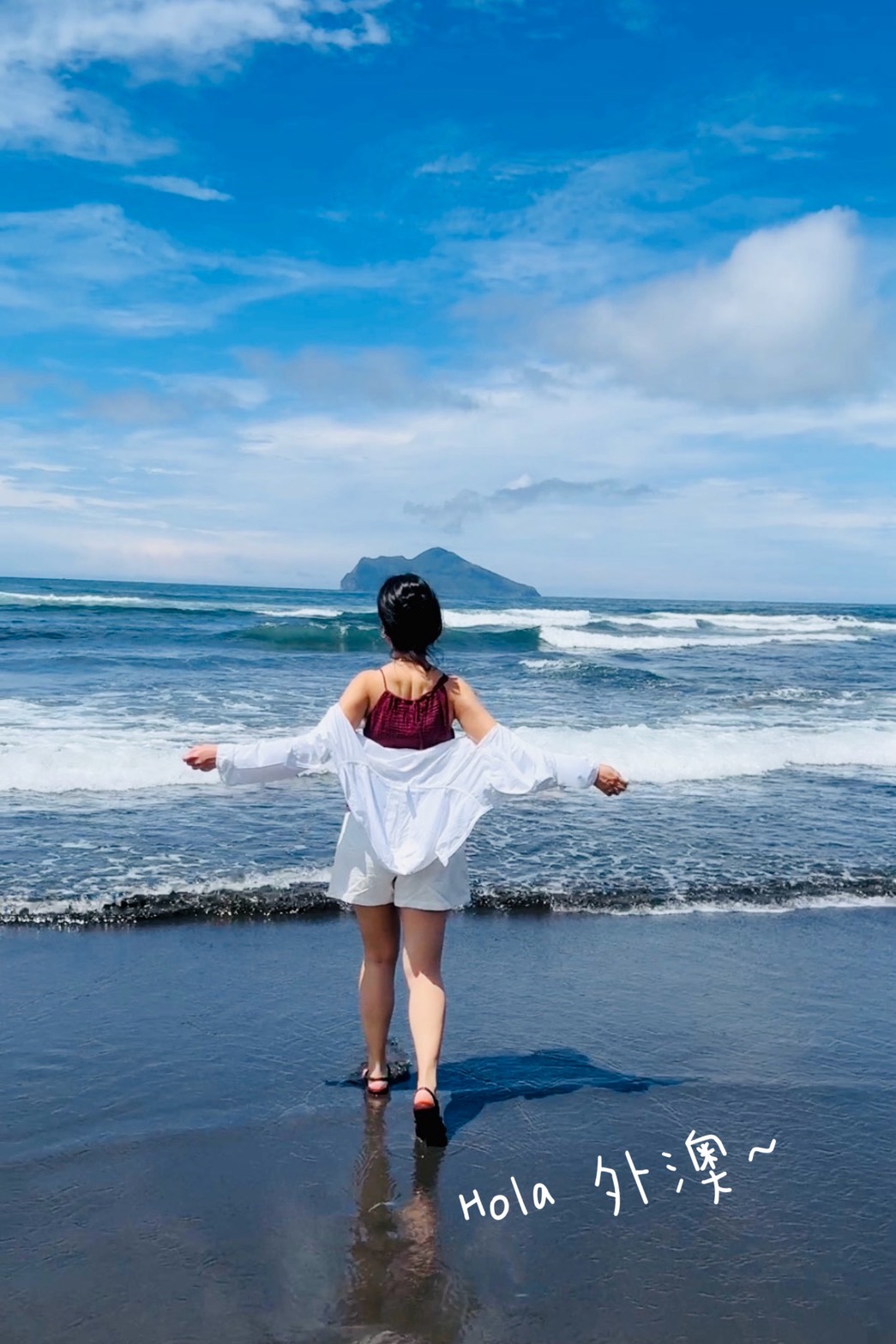 在外澳海邊張開雙臂看海，沙灘上寫著 Hola 外澳，背景是龜山島